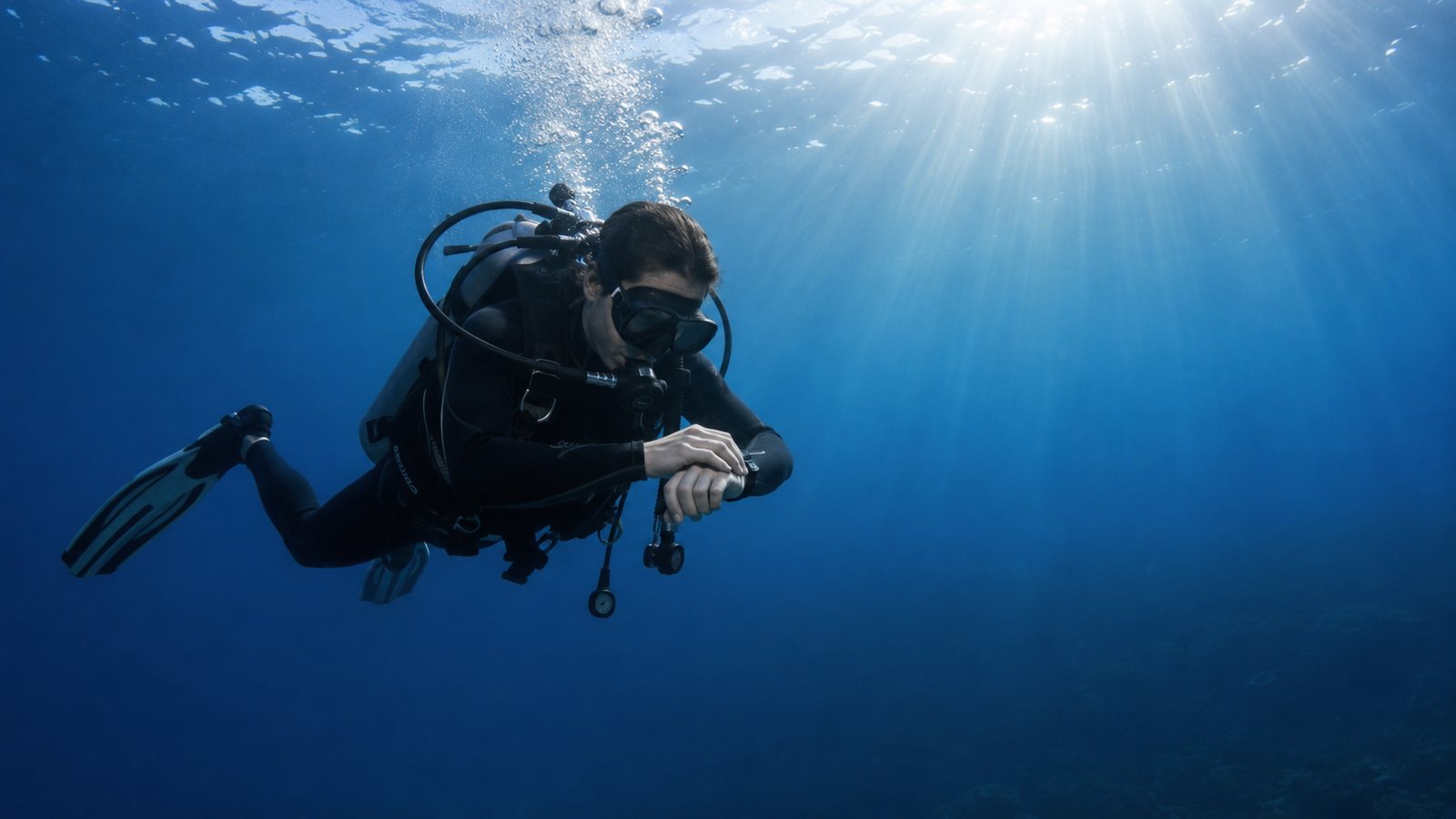 Scuba diver descending along a reef wall